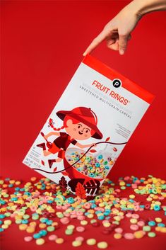 a hand reaching for a bag of fruit rings on top of a pile of sprinkles