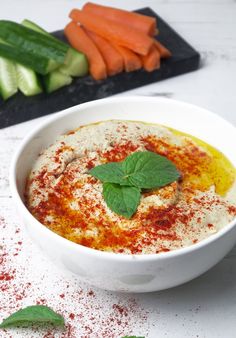 a white bowl filled with food next to sliced cucumbers