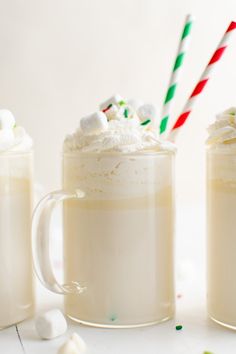 two mugs filled with hot chocolate and marshmallows next to candy canes