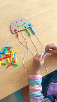 a child is making a kite made out of plastic pegs and colored pencils