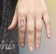 a woman's hand with a cat tattoo on her left thumb and the word cats written in black ink