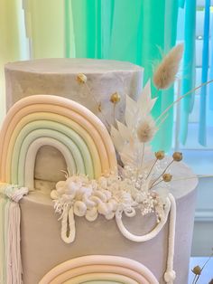 a three tiered cake decorated with rainbows and flowers