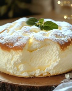 a cake with powdered sugar and green leaves on top sitting on a wooden plate