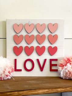 valentine's day decorations with paper hearts and pom poms on a shelf