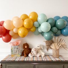 there is a bunch of balloons hanging on the wall next to a teddy bear and other items