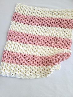 a pink and white crocheted blanket laying on top of a table