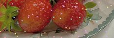 two strawberries are sitting on a plate with green leaves and sprinkles