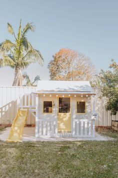 a small white house with a yellow slide