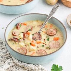 two bowls of soup with sausages, potatoes and parsley on the table next to it