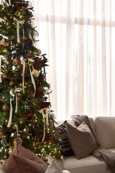 a living room with a christmas tree decorated in brown and white ribbons on the walls