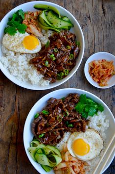 two bowls filled with rice, meat and veggies next to chopsticks