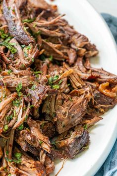 a white plate topped with sliced beef and garnished with parsley