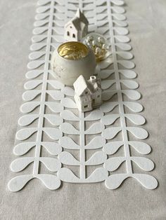 a table topped with white paper cutouts and a small house on top of it