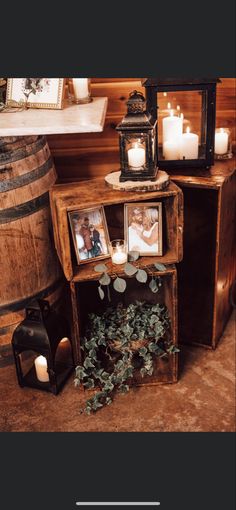 a table with candles and pictures on it next to a wine barrel filled with greenery