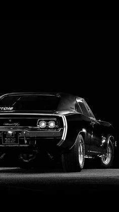 a black and white photo of an old muscle car in the dark with its hood up