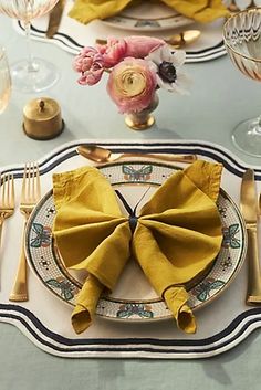 the table is set with yellow napkins and place settings for two people to sit at