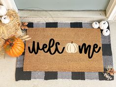 a welcome mat on the front door with pumpkins and hay