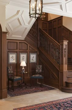 an ornate staircase with chandelier and wooden paneling in a large home setting