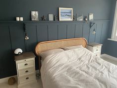 a bed sitting in a bedroom next to a white dresser and window with pictures on the wall