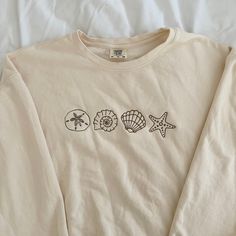 three seashells and starfish embroidered on a long sleeved t - shirt