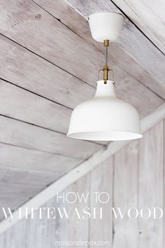 two white lamps hanging from the ceiling in a room with wood paneling and planked walls