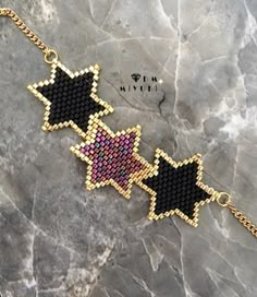 two black and pink stars on a gold chain