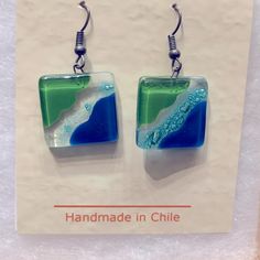 a pair of earrings with blue, green and white glass in the shape of waves