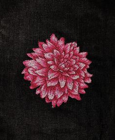 a pink and white flower on black fabric