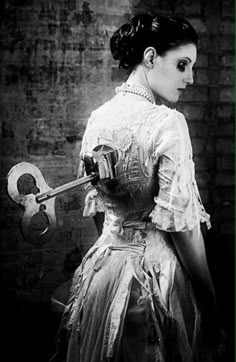 a woman in an old fashion dress holding a wrench