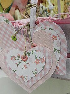 three heart shaped tags hanging from a string on a table with other items in the background