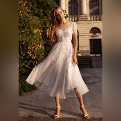 a woman in a white dress is standing outside