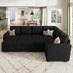 a living room with a large black couch and white rug on the floor in front of it