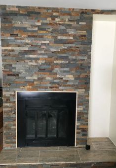 a stone fireplace with a black mantle and brown tile on the top part of it