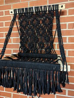 a black macrame hanging on a brick wall