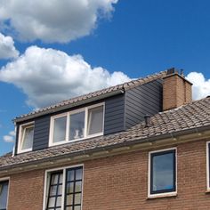 a brick building with two windows and a sky background