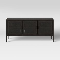 the sideboard is made from black rattan and has three doors on one side