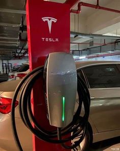 an electric car being charged at a charging station in a parking garage with tesla logo on it