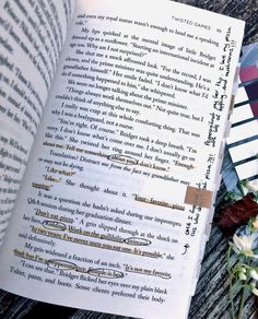 an open book sitting on top of a wooden table next to a bouquet of flowers