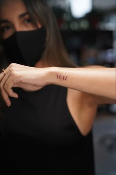 a woman wearing a face mask and holding her arm up with the word faith tattooed on it