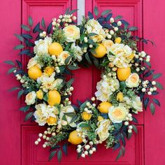 a wreath with lemons and white flowers on a red front door painted bright pink