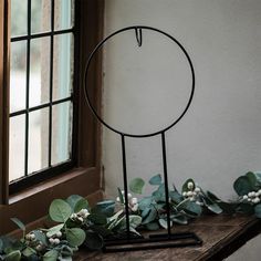 a metal stand with some plants on top of it next to a window sill