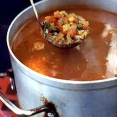 a ladle full of soup sitting on top of a stove