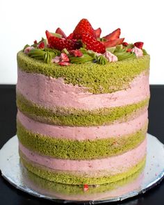 a green and pink cake with strawberries on top