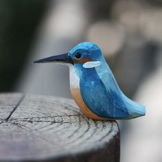 a small blue bird sitting on top of a wooden fence post next to a tree