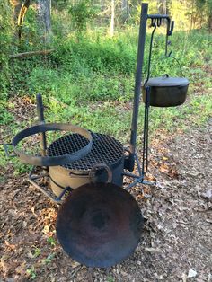 an old iron pot is sitting on the ground next to some metal pots and pans