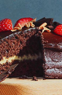 a chocolate cake with strawberries on the top and one slice cut out from it