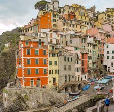 colorful buildings line the hillside above a body of water with boats parked in front of them