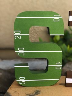 the letter b is made out of wood and has football stripes on it, along with two pieces of chocolate