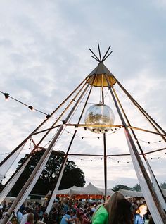 a group of people standing in front of a tent with lights hanging from the ceiling