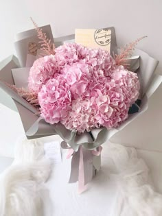 a bouquet of pink flowers sitting on top of a white cloth covered table next to a card